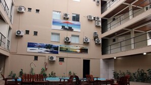 Un espacio interior de varios niveles con piscina, muebles de madera y unidades de aire acondicionado.