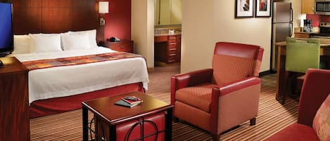 Ein Hotelzimmer mit Bett, Schreibtisch, Stuhl, einer Küchenzeile und einem Badezimmer.