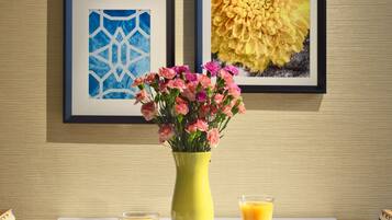A table with a vase of flowers, two muffins, and two glasses of orange juice.