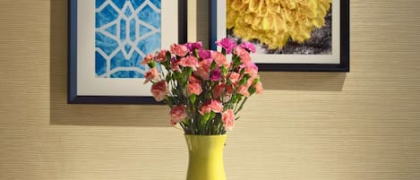Een tafel met een bloemenvaas, twee muffins en twee glaasjes sinaasappelsap.