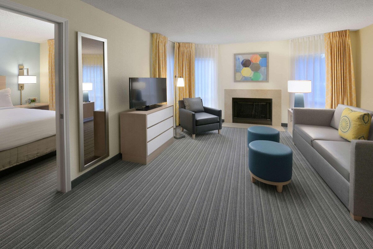Een hotelkamer met een bed, een televisie, een open haard, een bank en een salontafel.