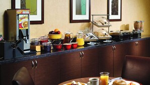 Un buffet de petit-déjeuner proposant des gaufres, des fruits et diverses boissons.