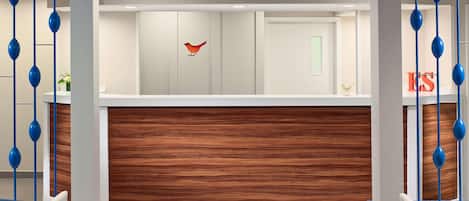 Un espace d’accueil moderne avec un mur lambrissé en bois, une décoration représentant un oiseau et des ornements bleus suspendus.