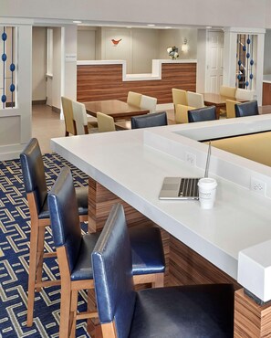 Een moderne hotel lobby met een lange receptiebalie, verschillende zithoeken en een houten accentmuur.