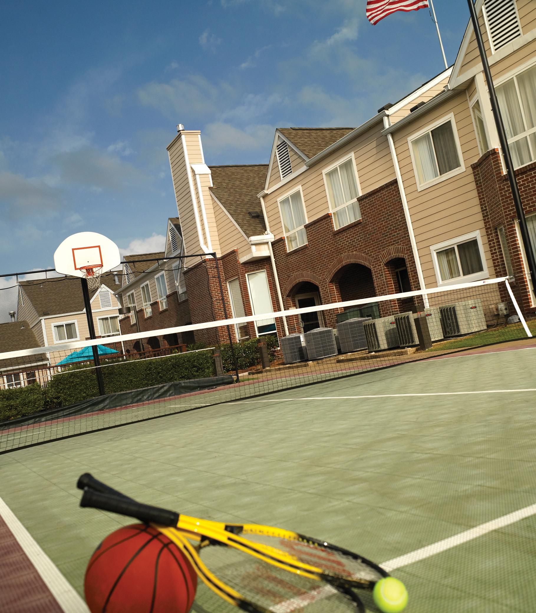 A tennis court with a net, a basketball hoop, and a tennis racket.