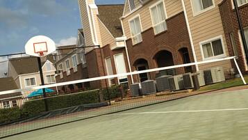 A tennis court with a net, a basketball hoop, and a tennis racket.