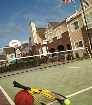Un terrain de tennis avec un filet, un panier de basket et une raquette de tennis.