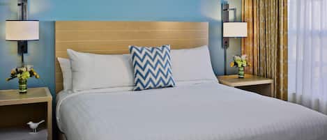 Een hotelkamer met een groot bed, twee nachtkastjes, een lade en een lamp.