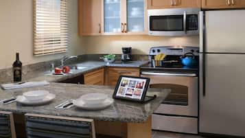 A modern kitchen with granite countertops, stainless steel appliances, and wooden cabinets.