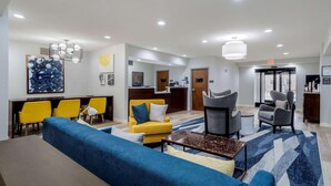 A modern hotel lobby with a blue sofa, yellow chairs, a reception desk, and a large window offering a city view. - Comfort Inn & Suites Lexington South (Lexington)
