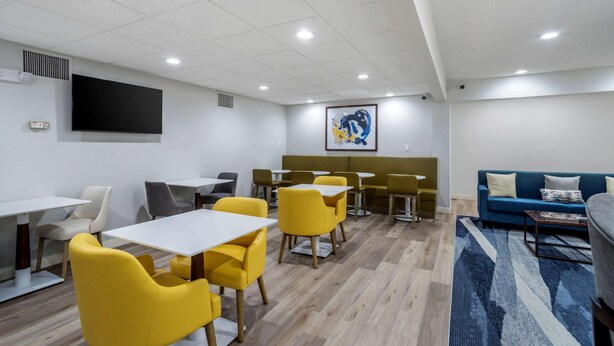 A modern room with yellow chairs and tables, a blue sofa, and a large painting on the wall. - Comfort Inn & Suites Lexington South (Lexington)