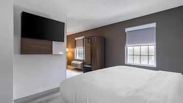 A modern hotel room with a large bed, a flat-screen TV mounted on the wall, a wardrobe, and a window with blinds.