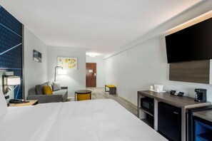 A hotel room with a large bed, a desk with a coffee maker, a TV, a sofa, and a small table. - Comfort Inn & Suites Lexington South (Lexington)