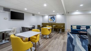 A modern room with yellow chairs and tables, a blue sofa, and a large painting on the wall. - Comfort Inn & Suites Lexington South (Lexington)