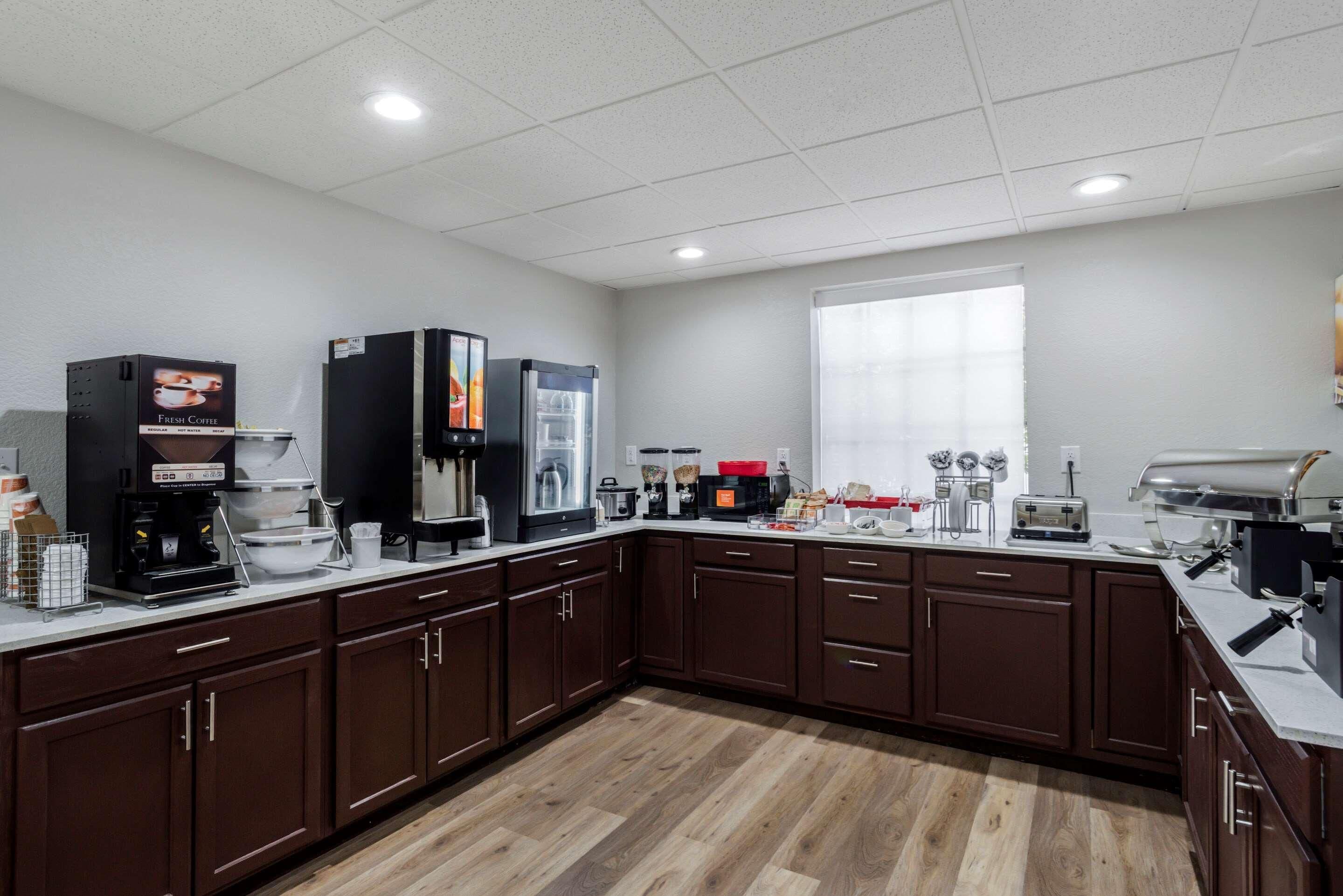 A modern kitchen with a coffee station, microwave, toaster, and a large window.