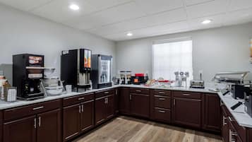 A modern kitchen with a coffee station, microwave, toaster, and a large window.