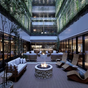 A modern atrium with a central fire pit surrounded by seating, glass walls, and greenery. - Good Nature Hotel Kyoto (Kyoto)