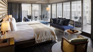 Een hotelkamer met een groot bed, een bank, een klein tafeltje met dienblad, en een stoel.