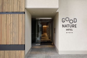 Een hotelentree met een houten gevel en een bord waarop 'GOOD NATURE HOTEL KYOTO' staat.