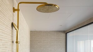 A modern bathroom with a freestanding bathtub, a gold showerhead, and a glass shower enclosure.