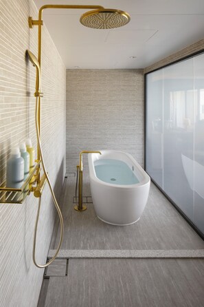 A modern bathroom with a freestanding bathtub, a gold showerhead, and a glass shower enclosure.