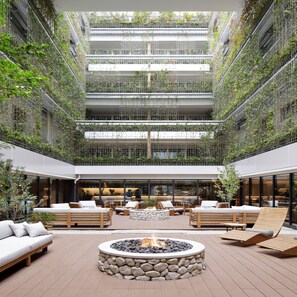 A spacious atrium with a central fire pit surrounded by seating areas, a high ceiling with greenery, and a modern architectural design. - Good Nature Hotel Kyoto (Kyoto)