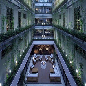 Un atrium à plusieurs niveaux doté d’un espace de détente central comprenant des canapés et des tables, le tout entouré de luxuriants jardins verticaux.