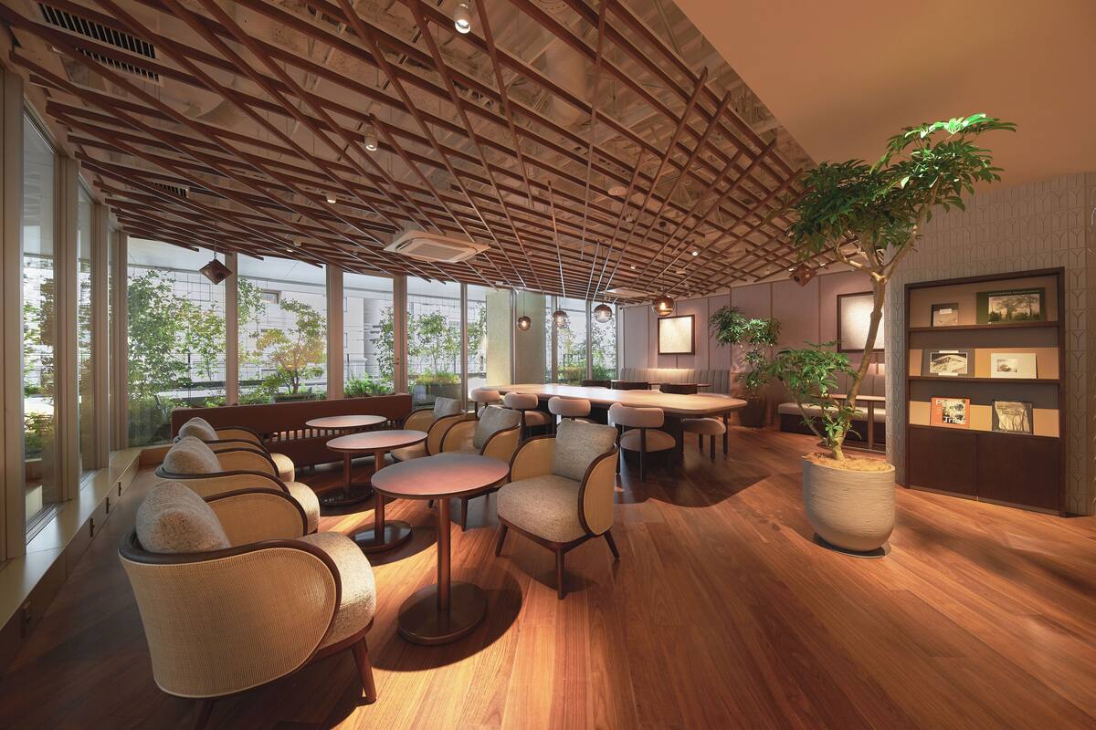 Un intérieur moderne avec un plancher en bois, des coins salon et de grandes fenêtres offrant une vue sur l’extérieur.