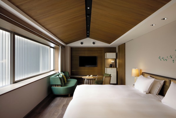 A hotel room with a large bed, a TV mounted on the wall, a desk with a lamp, and a seating area with a sofa and chairs. - Good Nature Hotel Kyoto (Kyoto)
