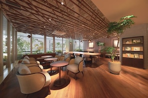 Un interior moderno con suelo de madera, zonas de estar y grandes ventanales que ofrecen vistas al exterior.