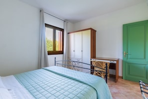 A bedroom with a bed, a desk, a wardrobe, and a green door. - Residence Vecchio Stazzo (San Teodoro)