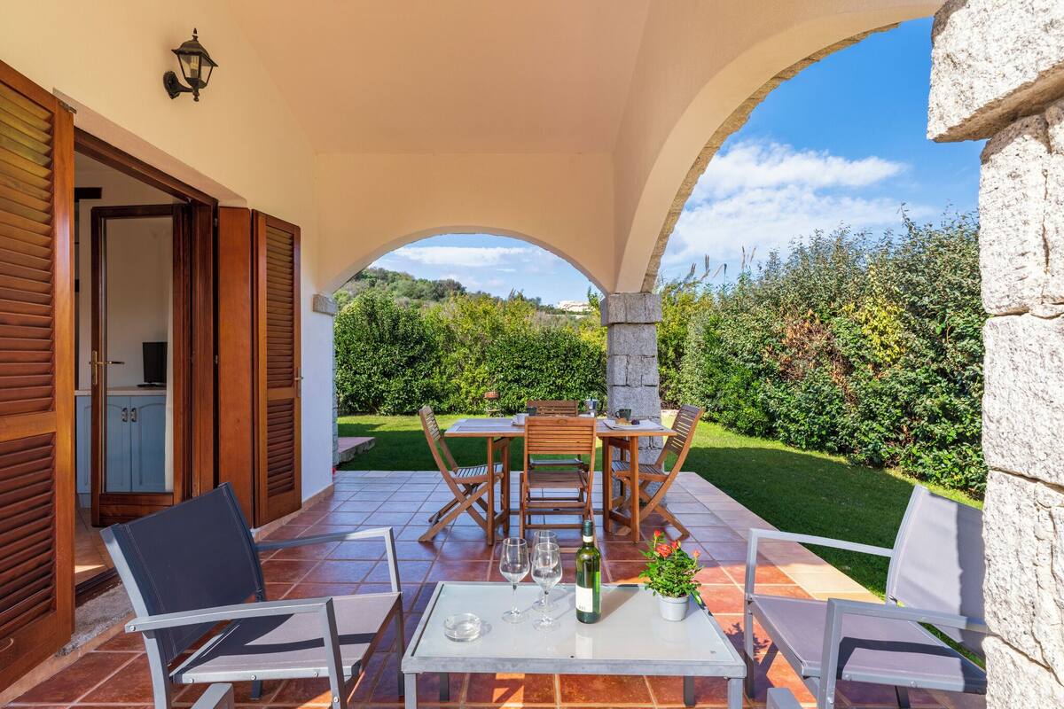 Une terrasse extérieure avec une table, des chaises et une bouteille de vin.