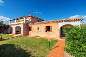 A two-story building with a tiled roof, a stone archway, and a well-maintained lawn. - Residence Vecchio Stazzo (San Teodoro)