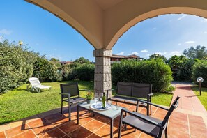 A patio with a table, chairs, and a bottle of wine.