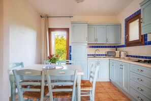 A kitchen with light blue cabinets, a white countertop, and a dining area with a table and chairs.