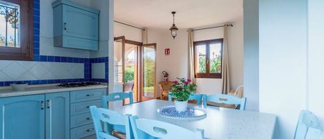 A kitchen with blue cabinets, a white table, and chairs.