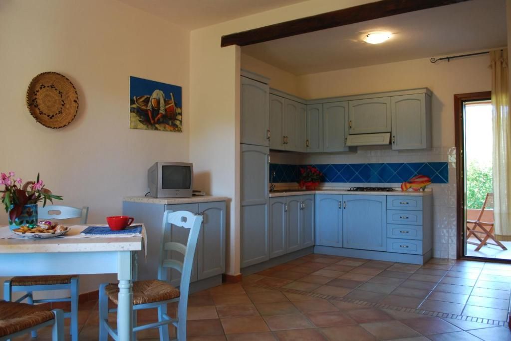 A kitchen with light blue cabinets, a tiled backsplash, and a dining area with a table and chairs.