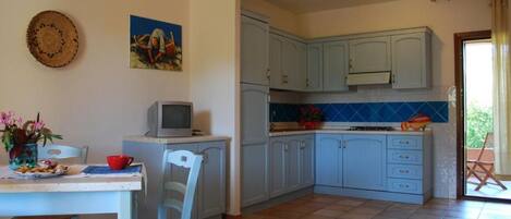 A kitchen with light blue cabinets, a tiled backsplash, and a dining area with a table and chairs.
