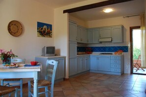 Cozinha com armários azul-claros, painel de azulejos e área de refeições com mesa e cadeiras.