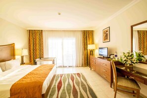A hotel room with a bed, a desk, a chair, a television, and a bathroom.