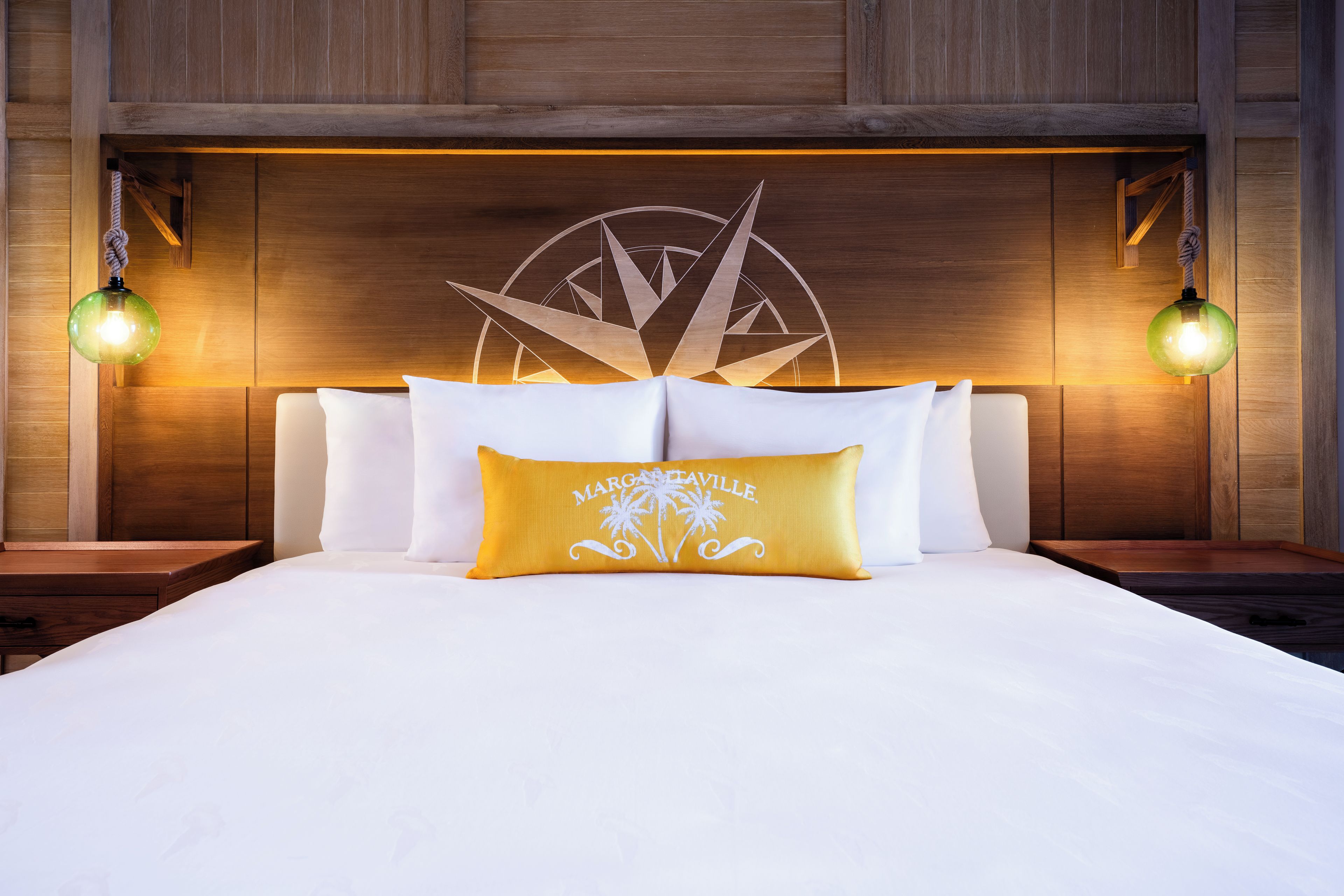 Een net opgemaakt bed met witte lakens en een enkel decoratief kussen.