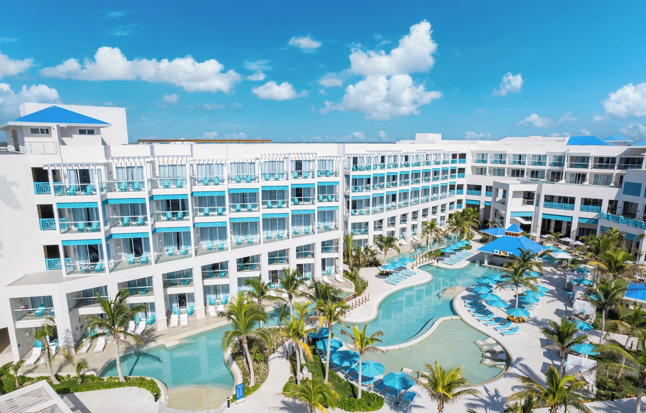 A resort with multiple balconies, a central swimming pool, and palm trees.