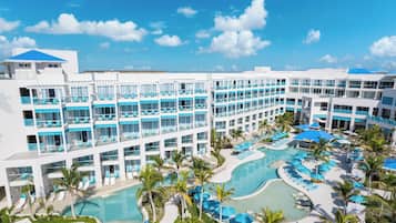 Un resort con varios balcones, piscina central y palmeras.