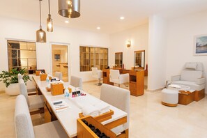 A modern spa room with a long reception desk, multiple seating areas, and a large window providing natural light. - Margaritaville Island Reserve Riviera Maya (Puerto Morelos)