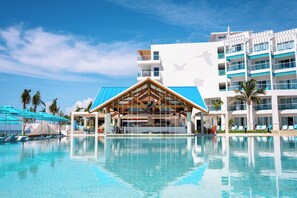 A resort with a large pool, a covered bar area, and a multi-story building with balconies. - Margaritaville Island Reserve Riviera Maya (Puerto Morelos)
