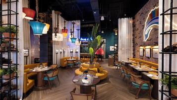 A restaurant interior with wooden flooring, yellow seating, and various hanging lights.