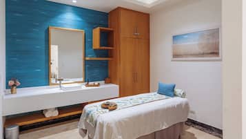 Une salle de bain moderne avec un grand miroir, des meubles en bois, un meuble-lavabo blanc et un lit avec un oreiller bleu.