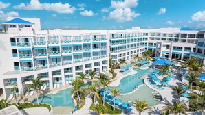 Un resort con varios balcones, piscina central y palmeras.
