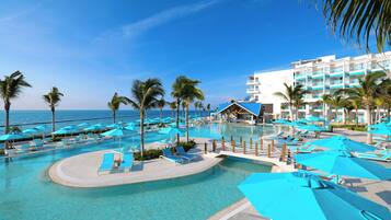 A resort pool area with clear blue water, lounge chairs, and umbrellas.