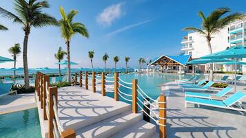 A resort pool area with clear blue water, palm trees, and lounge chairs.